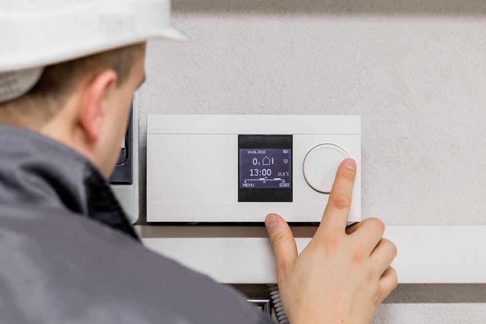 HVAC technician adjusting thermostat in New Jersey home